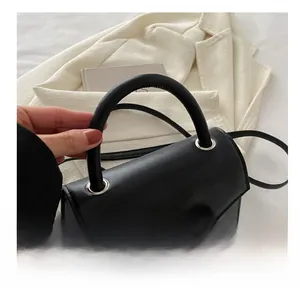Close-up of comfortable handle on black crossbody bag with silver bow decoration