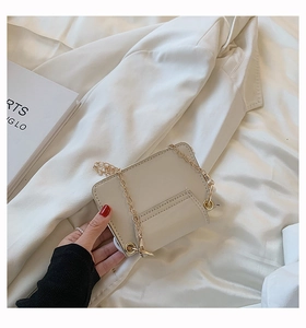 Detail einer cremefarbenen Mini-Leder-Umhängetasche mit Goldkette und feinen Nähten
