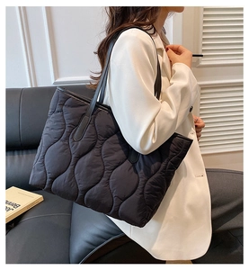 Gros plan sur le sac cabas matelassé noir avec coutures ondulées et fines bandoulières