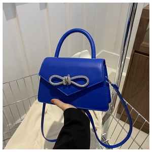Detail of blue leather handbag with silver rhinestone bow buckle and carry handle