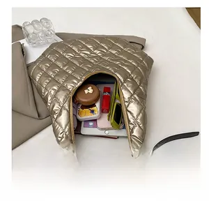 Top view of gold quilted tote bag interior holding a phone, sunglasses and cosmetics