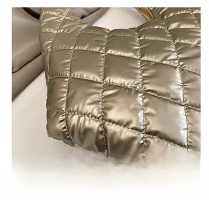 Detail shot of golden quilted puffer tote bag fabric with glossy metallic texture and stitching