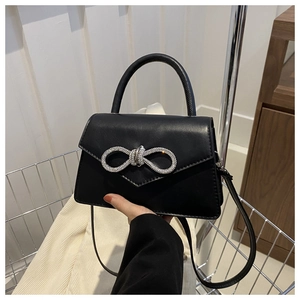 Close-up of black handbag with sparkling silver rhinestone bow clasp and leather texture