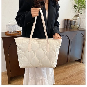 Quilted wave pattern tote bag in beige shown with elegant city-style outfit