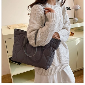 Detail of grey quilted tote bag with large wave stitching and long leather straps