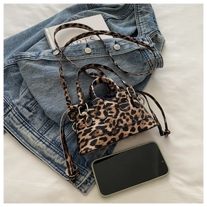 Mini leopard print tote bag with double handles and drawstring closure on fabric background