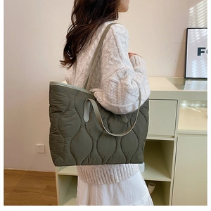 Olivgrüne gesteppte Shopper-Tasche mit Wellenmuster als Schultertasche am Model