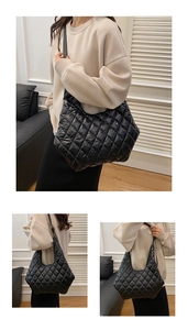 Close-up of quilted black nylon tote bag showing soft padded texture and shoulder strap