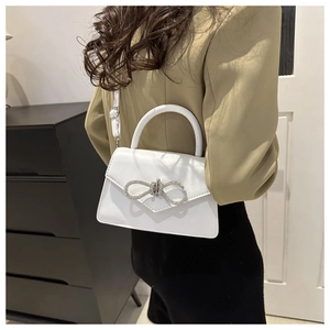 White bow handbag with crystals and stitch detail shown as crossbody on model