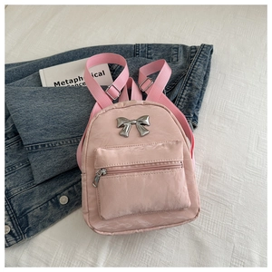 Mini sac à dos rose avec nœud argenté et poche zippée sur fond de lin blanc doux