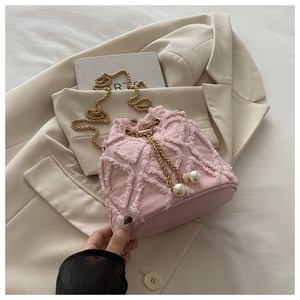 Pink denim bucket bag featuring quilted tassel trim, gold chain, and pearl accents