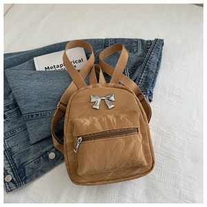 Gros plan sur un mini sac à dos kaki avec texture plissée et détail de nœud argenté