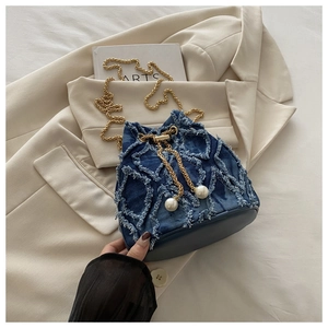 Detail of denim bucket bag with quilted fraying, pearl drawstring and gold chain strap