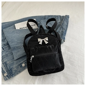 Gros plan du mini sac à dos noir en tissu froissé avec un nœud en métal argenté