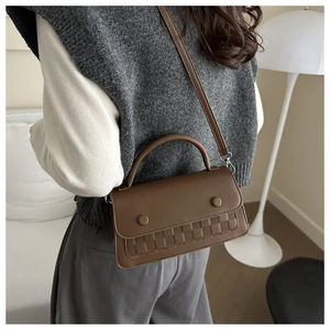Detailed view of brown leather crossbody bag featuring woven texture and decorative buttons