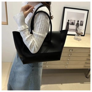 Close-up of black textured tote bag with double handles in a lifestyle setting