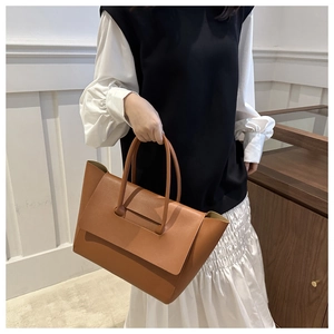 Close-up of brown vintage leather tote bag with cylindrical handles and flap closure
