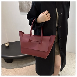 Detail of burgundy leather winged tote bag with modern minimalist layered structure