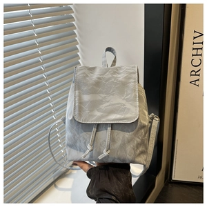 Détail d'un mini sac à dos gris clair avec texture froissée et fermeture à cordon