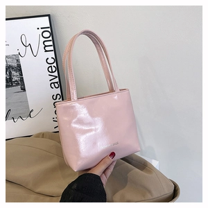 Gros plan du sac à main en cuir verni rose clair avec finition brillante et lettrage