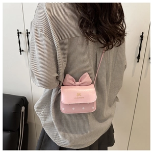 Petit sac bandoulière rose avec nœud et pois blancs, porté par un mannequin de dos