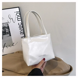 Détail du petit sac blanc en cuir verni brillant avec l'inscription FASHION & BAGS