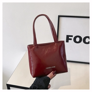 Détail du petit sac à main bordeaux en cuir verni brillant avec lettrage blanc