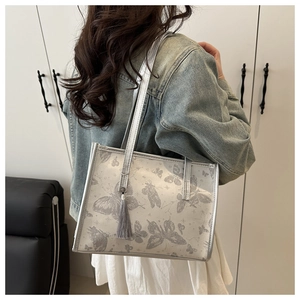 Close-up of butterfly print detail and tassel on silver-grey shoulder tote bag