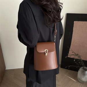 Vintage brown leather bucket bag with gold horse-shoe buckle shown on a model