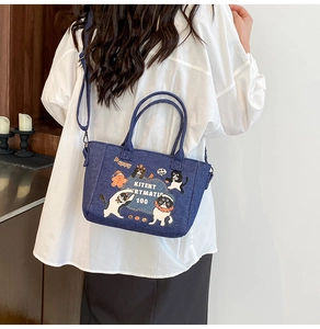 Detail view of denim tote bag featuring cartoon cat prints and adjustable shoulder strap