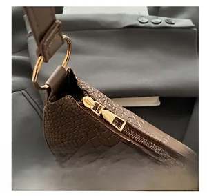 Detail of dark brown faux crocodile leather bag with gold metal zipper and hardware