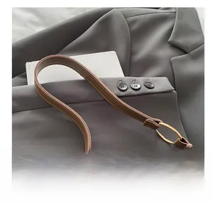 Detail of brown crocodile pattern shoulder bag with gold rings on grey blazer