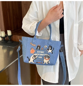 Detailed view of light blue denim bucket bag featuring cute black and white cat prints