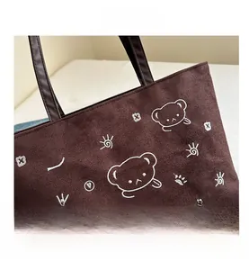Detail of dark brown tote bag with cute white line embroidery and sturdy handles