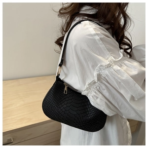 Close-up of black snake-patterned baguette bag featuring gold metal rings and retro texture
