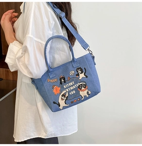 Detail of denim tote bag showing cat patterns and detachable adjustable shoulder strap