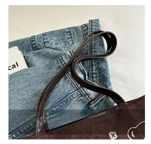 Detail of plush brown tote bag with white flower embroidery and faux leather handle