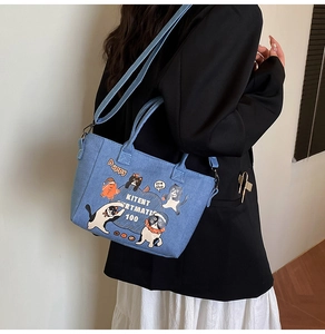 Detail of blue denim tote bag featuring cartoon cat prints and adjustable shoulder strap