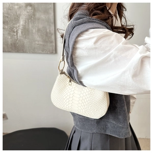 Detail of white crocodile embossed shoulder bag with elegant gold metal ring hardware