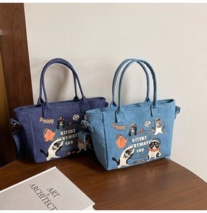 Close-up of cat print denim tote bags in dark and light blue with metal buckles