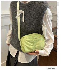 Detail of light green nylon crossbody bag showing front pocket and soft texture