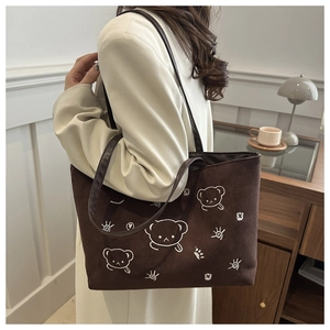 Macro detail of dark brown suede tote bag with white bear embroidery and leather straps