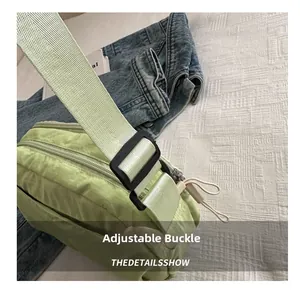 Detail of adjustable buckle and wide woven strap on light green nylon crossbody bag