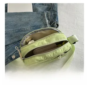 Detailed top view of light green nylon crossbody bag showing dual zipper compartments