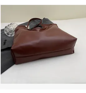 Detail of soft deep brown leather tote bag on white surface with business casual backdrop
