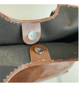 Detailed macro of silver magnetic snap closure and texture of brown oil wax tote bag