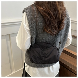 Detailed back view of a minimalist black nylon crossbody bag worn on a casual outfit