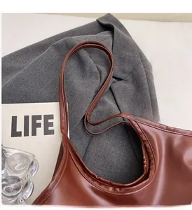 Detail showing high-quality stitching and durable double straps on a brown leather tote bag