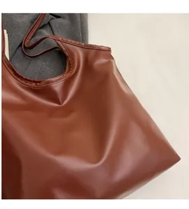 Detailed view of the soft brown synthetic leather texture on a spacious tote bag