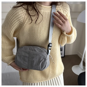 Gray nylon crossbody bag on model with adjustable strap for casual daily commuting